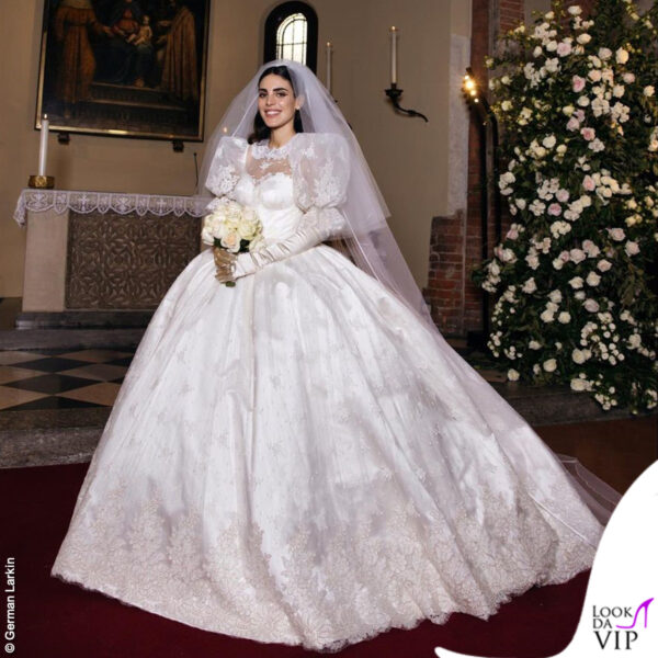 Per la sposa un vestito bianco vaporoso e principesco con colletto in pizzo, maniche a sbuffo e ampia gonna a meringa, con decorazioni floreali. Una creazione di Alessandra Rich 