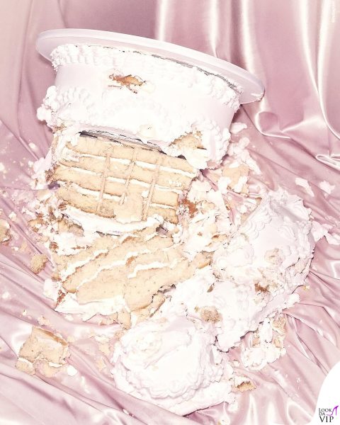 Simbolico scatto con torta nuziale rovesciata su tessuti rosa.