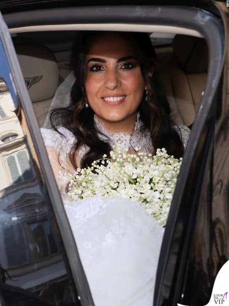 La sposa mostra un sorriso raggiante stringendo il bouquet sul sedile.