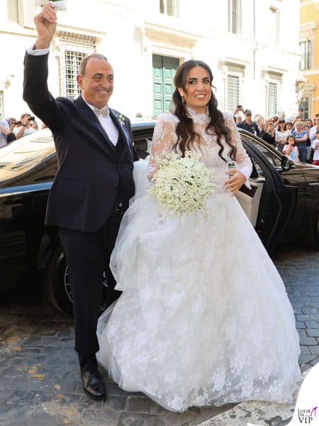 La sposa Francesca Brienza saluta con il padre davanti alla folla.