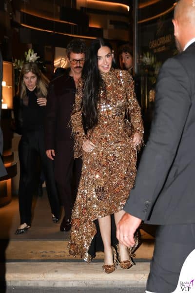 Primo piano su Demi Moore in total look oro Gucci: abito ricamato con frange preziose, gioielli scintillanti e acconciatura naturale. Eleganza iconica al party 2025.