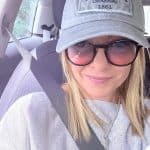 Giorgia Meloni con cappellino grigio e occhiali da sole in auto.