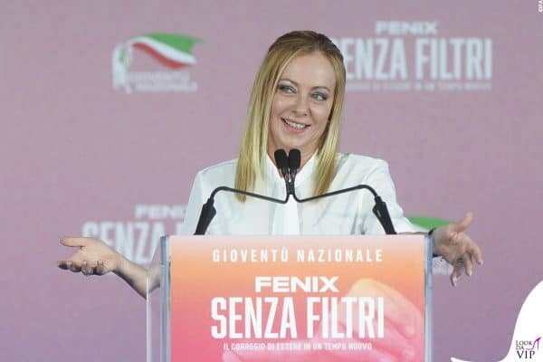 Sul palco della kermesse “Senza Filtri”, la premier si mostra sorridente con camicia bianca e make-up naturale.