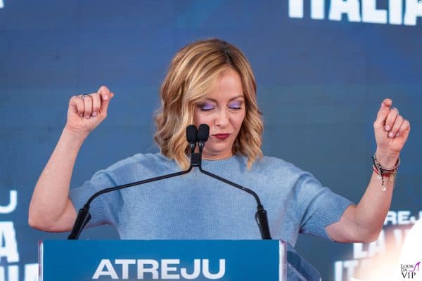 Sul palco di Atreju, Giorgia Meloni opta per un maglioncino celeste e un trucco occhi decisi in tonalità lilla.