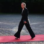 Giorgia Meloni con completo nero e clutch mentre cammina su un tappeto rosso.