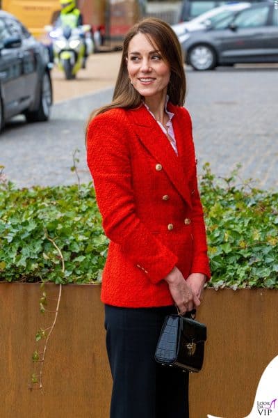 Contrasti decisi per Kate Middleton, che abbina il rosso intenso del blazer a una borsa nera lucida dallo stile classico