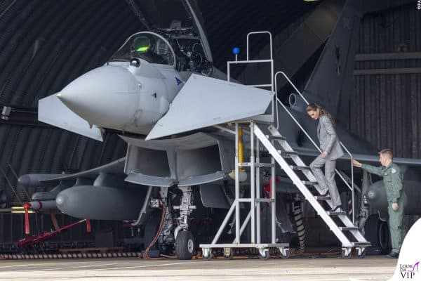Con espressione attenta, Kate ascolta i dettagli tecnici del jet da combattimento.